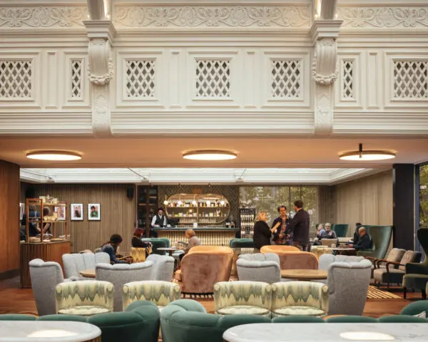 Green, pink and grey chairs in front of a gold bar where people are standing.