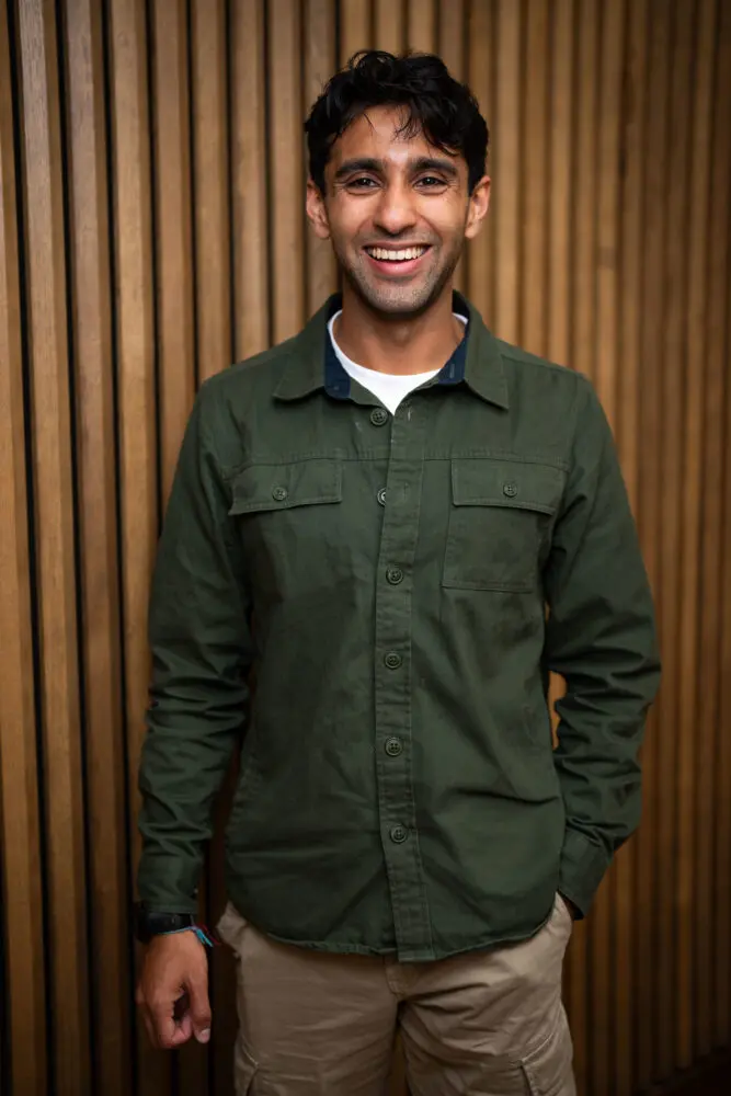 Seth Daood. A man with short dark hair wearing a white t-shirt with green shirt over the top.