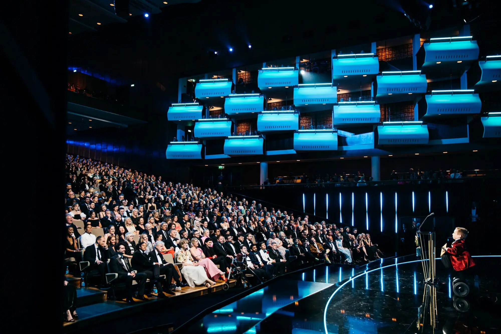 Lenny Rush. A young white man in a red velvet jacket on a Segway onstage during the 2024 BAFTA Television Awards with P&O Cruises at The Royal Festival Hall.