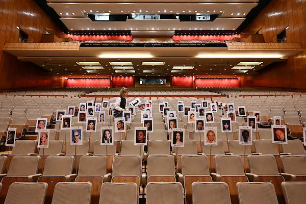 A person laying out images of attendees on seats in the Royal Festival Hall, Southbank Centre.
