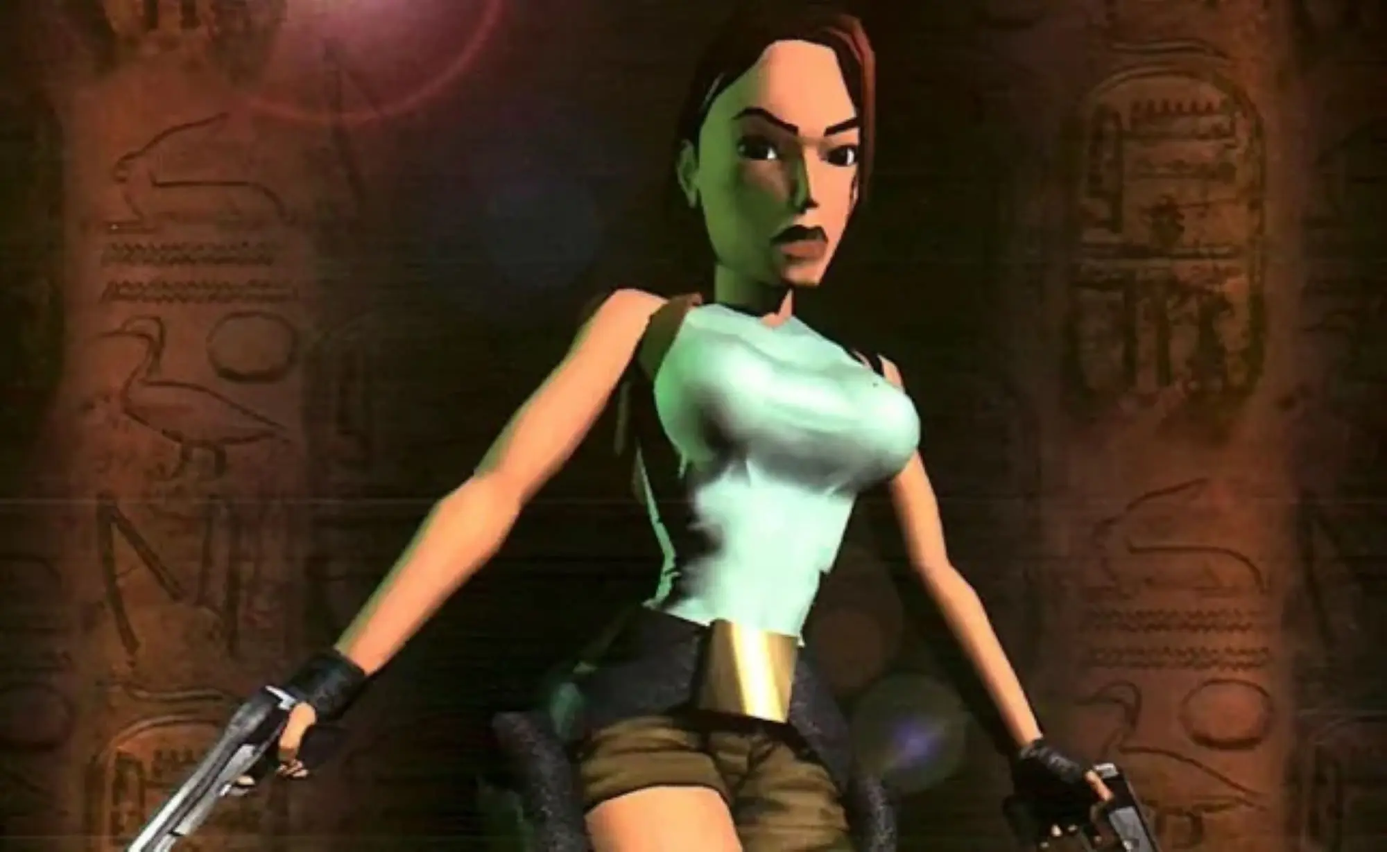 A still of Lara Croft from the Tomb Raider game. She is a female figure with brown hair wearing a white tank top and short brown shorts with a gun holster on it.